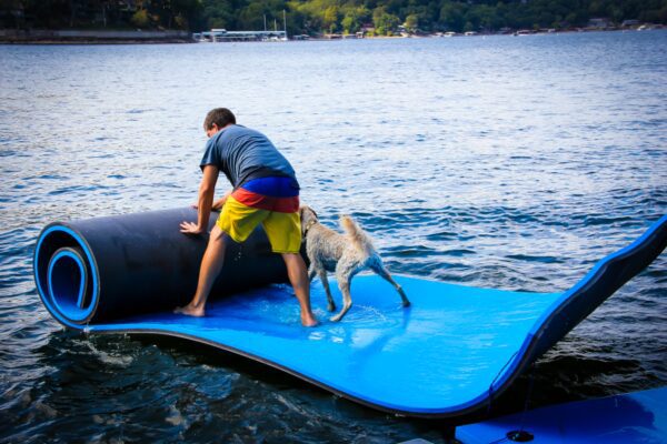 Man with a dog rolling a floating mat