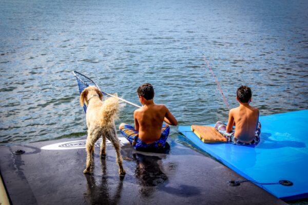 Kids fishing from a floating mat with their dog