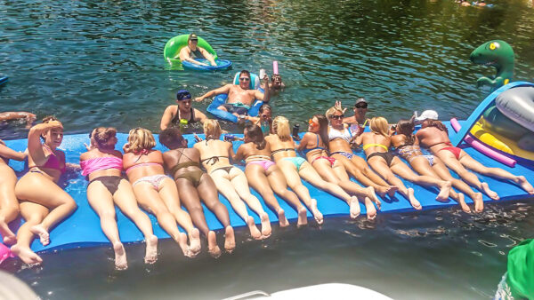 Tons of women laying out on a floating water mat